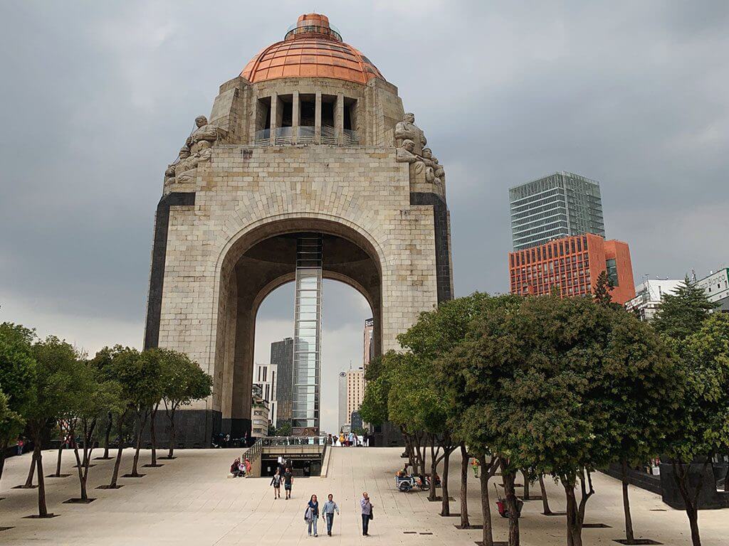 the monument of the revolution with trees in the foreground