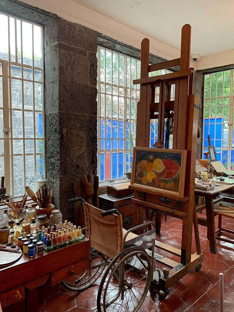 Frida Kahlo's wheelchair sits in front of a canvas holding her famous fruit painting in her studio at la casa azul, Coyoacan