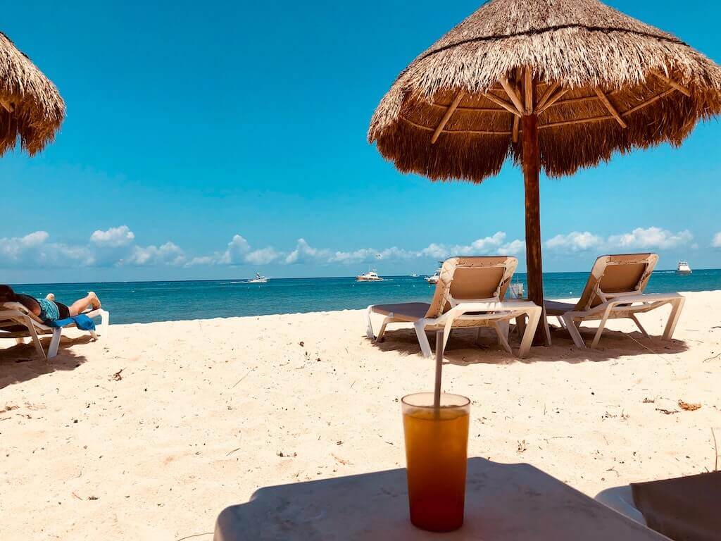 beach chairs under a palapa on a whitesand beach on Cozumel