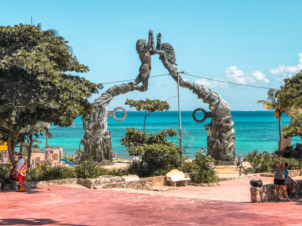 looking past the Portal Maya sculpture at parque fundadores in playa del Carmen, with the caribbean sea in the background