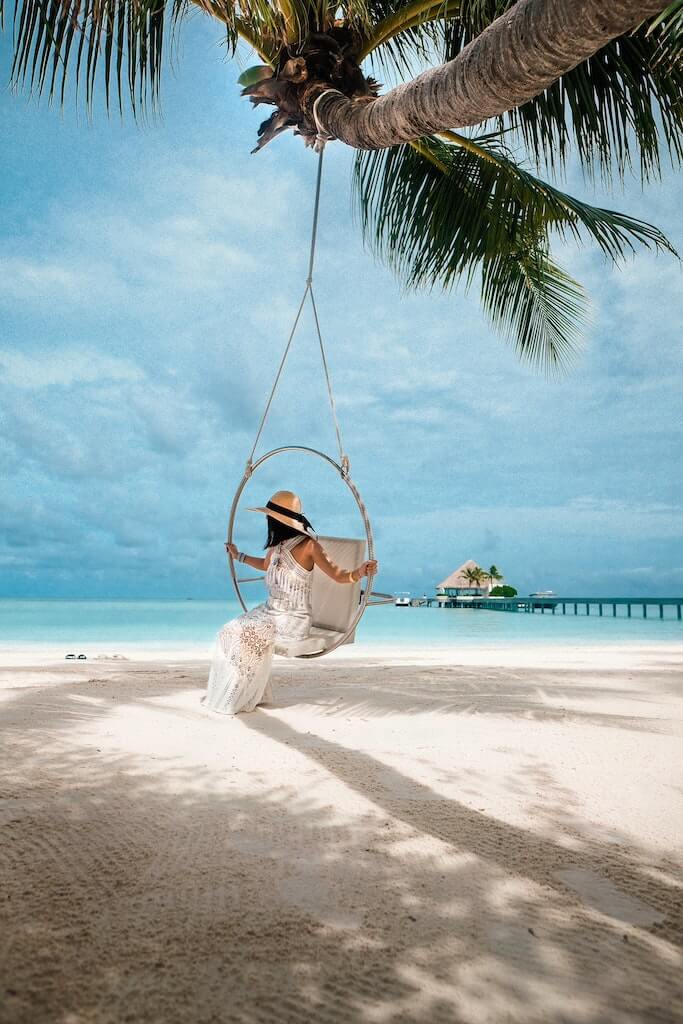 woman in sundress sitting in swing with caribbean sea in the background