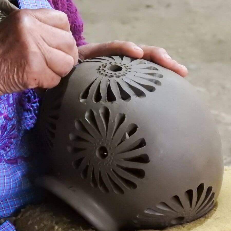 a woman carves Barro Negro Pottery in San Bartolo Coyotepec, Oaxaca