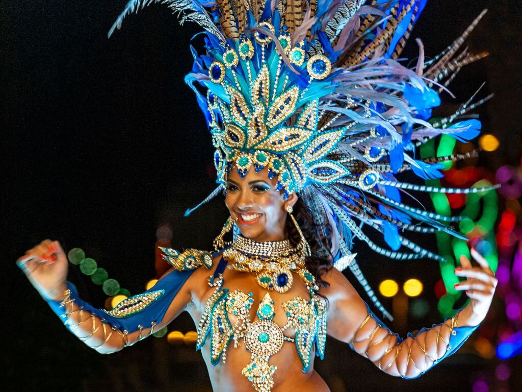 A dancer dressed in a vibrant outfit with blue feathers and beads for Carnival Festival in Mexico