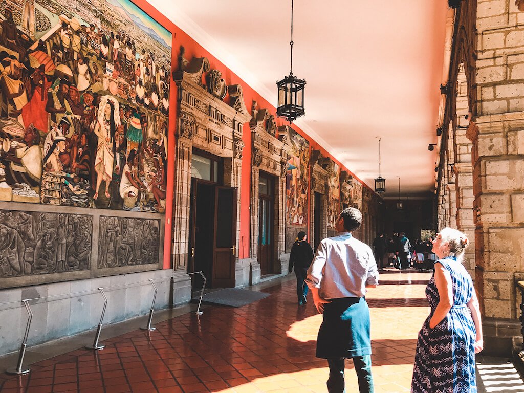 travelers admiring the Diego Rivera Murals at the Palacio Nacional in Mexico City