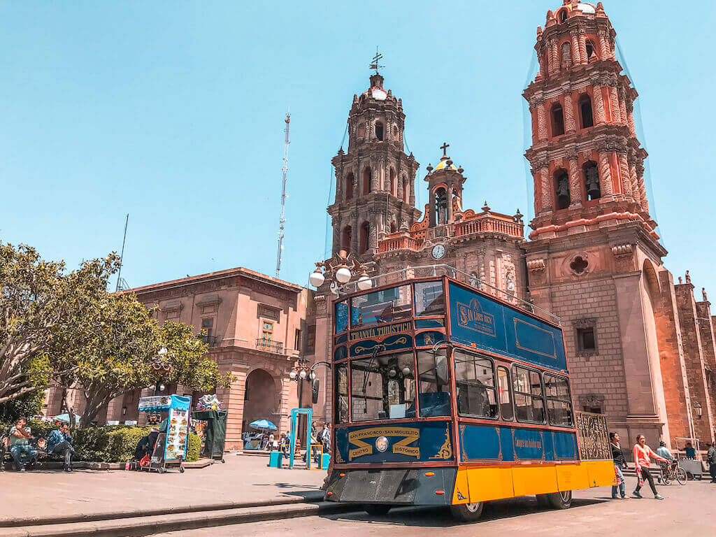 town square in San Luis Potosí with blue and yellow tourist tram parked in front of cathredral 