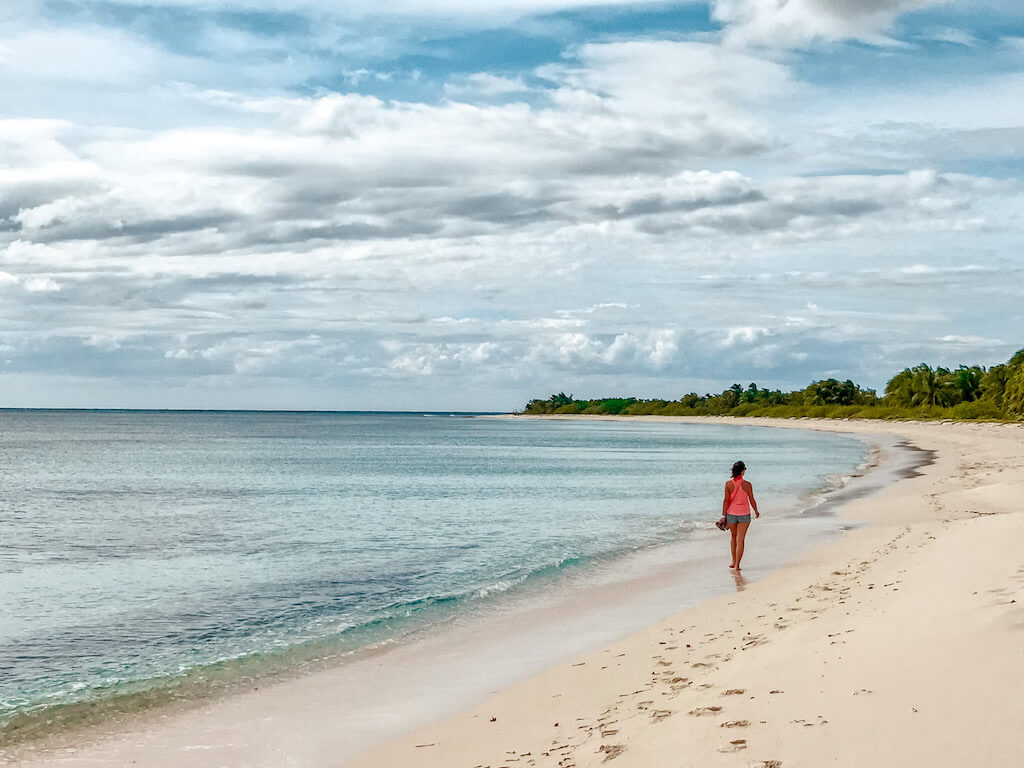 woman walks alone down El Cielo beach in Cozumel, Mexico