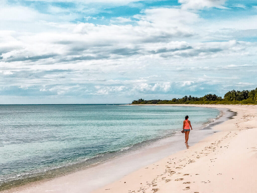 A distant shot of Janine walking along the whitesand shores of El Cielo Beach in Punta Sur Eco Park, Cozumel, Mexico