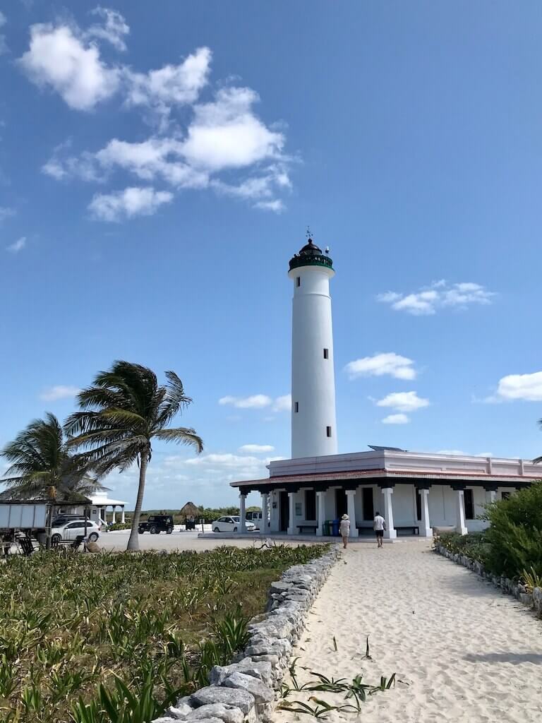 Cozumel's Punta Sur Lighthouse in the distance with two palm trees next to it