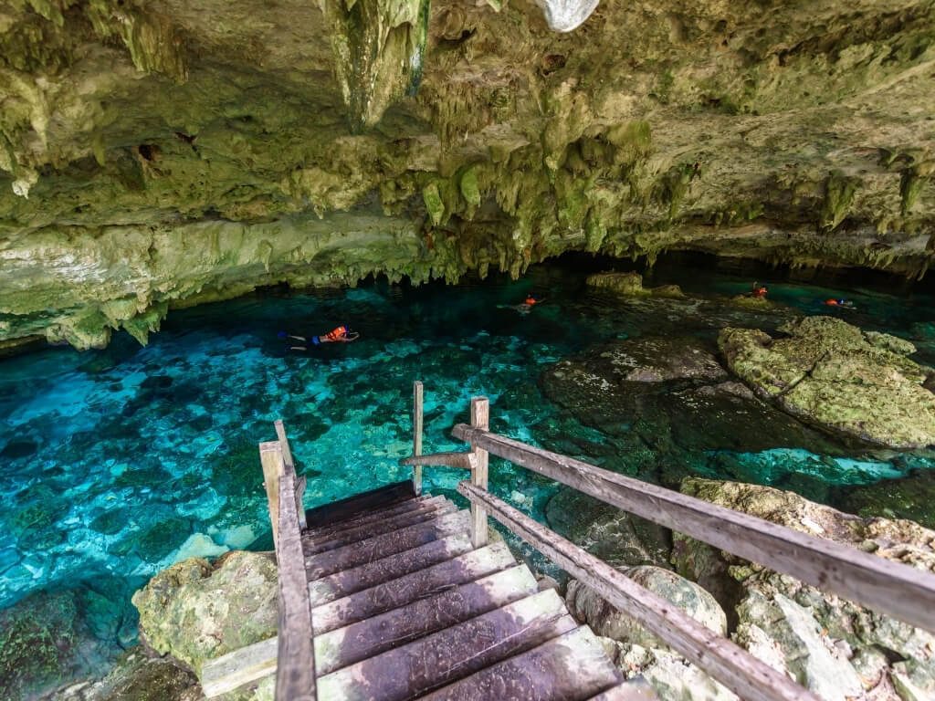 the dos ojos cenotes are partially covered by overhanging rocks