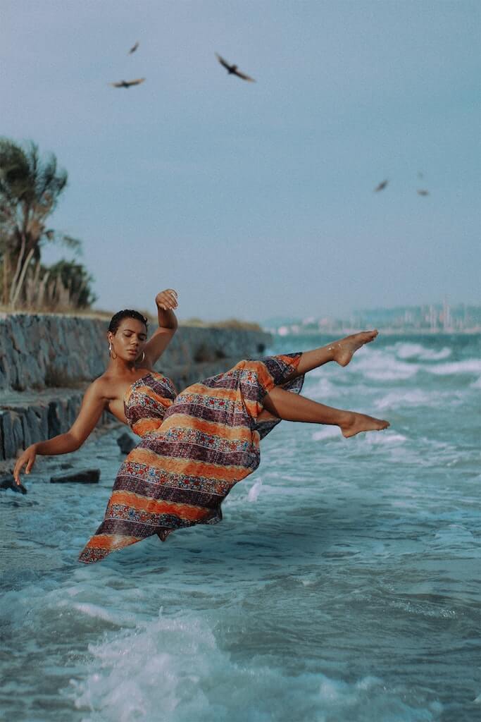 woman in sundress jumping into the ocean