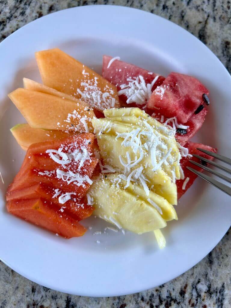 plate of tropical fruit with shaved coconut on top