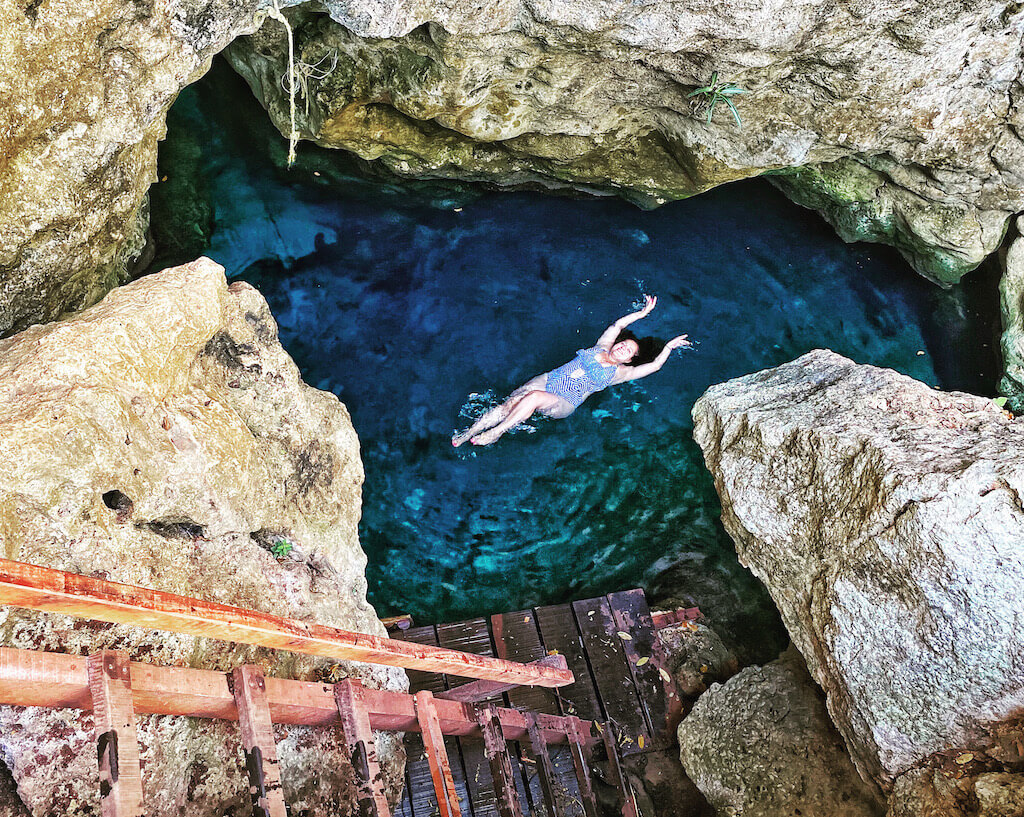 solo female traveler swimming in a cenote in Mexico