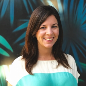 portrait of a brunette woman with palm tree mural in the background