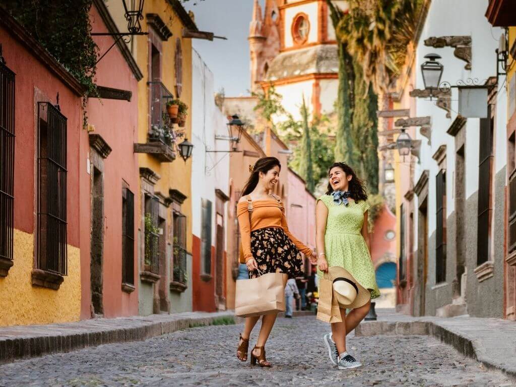 two women laugh as they walk down a cobblestone street in San Miguel de Allende, Mexico