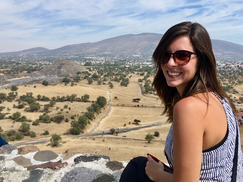 A woman sits on top of the Pyramid of the Sun at Teotihuacan, Mexico