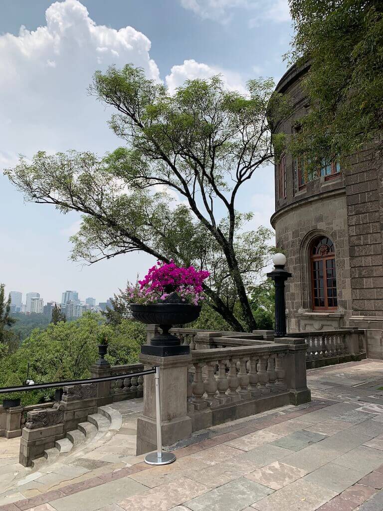 The lush gardens and stone architecture of Chapultepec Castle in Mexico City, set against a backdrop of modern skyscrapers, offering a serene escape within the high-altitude urban environment.