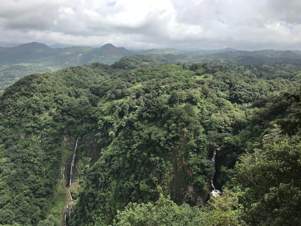 lush green hillside with waterfalls cascading from the hills. 