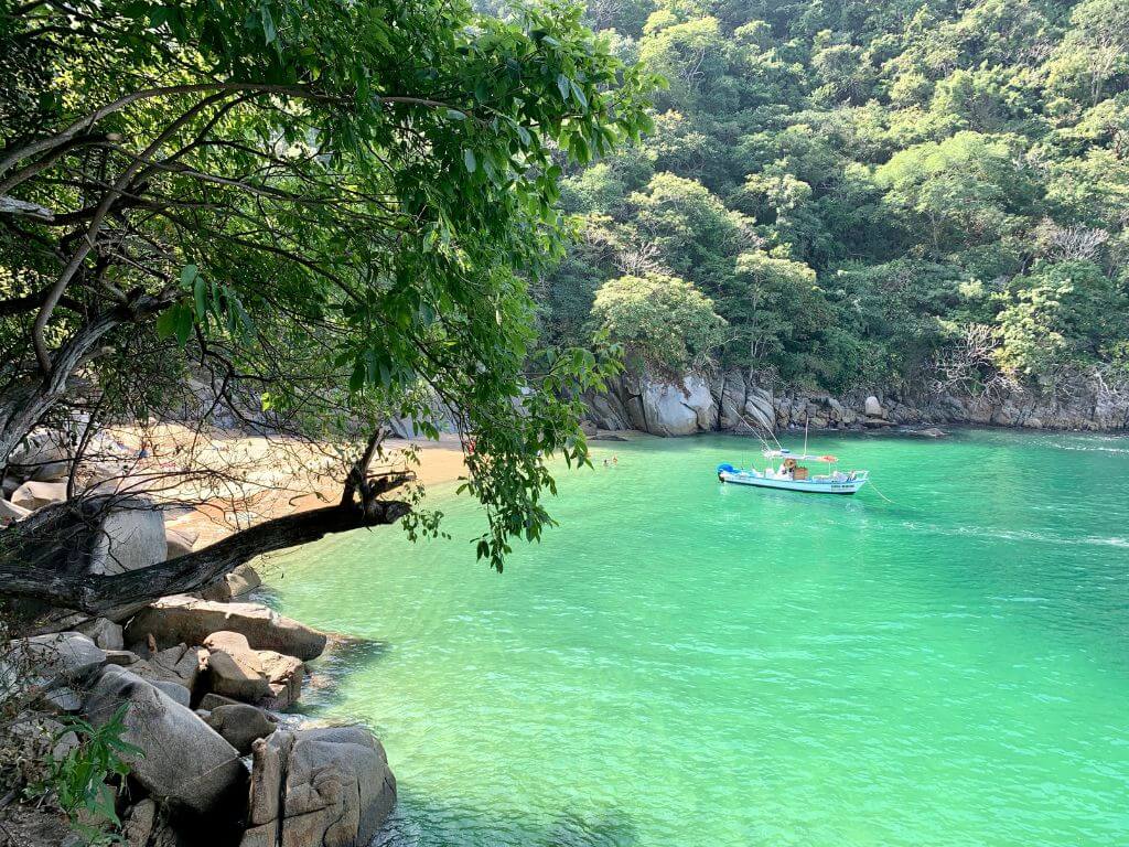 a panga boat floats in the bay off Playa Colomitos