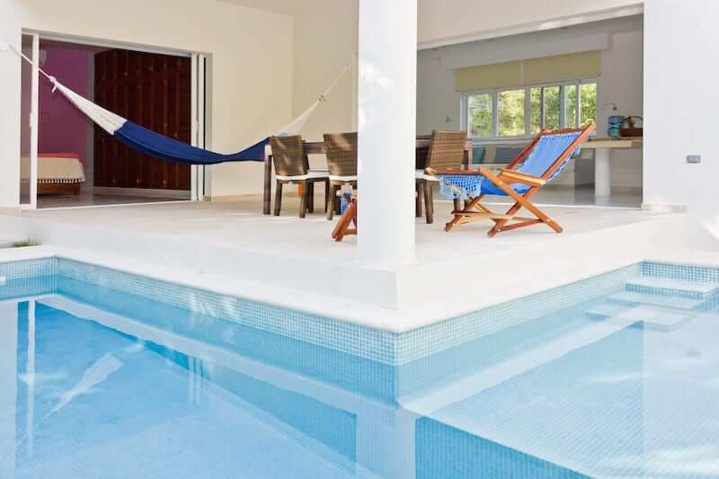 looking across the pool toward a patio and living area of an airbnb in playa del carmen, mexico