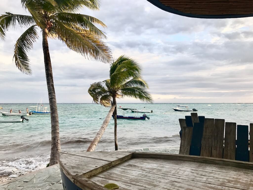 Boat shaped table overlooking Caribbean sea and anchored boats in Playa del Carmen