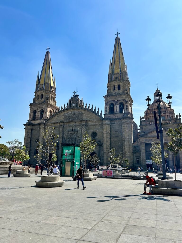 The main cathedral of Guadalajara sits on the edge of the famous Plaza Guadalajara. Visitors take photos of the attractions in the distance.