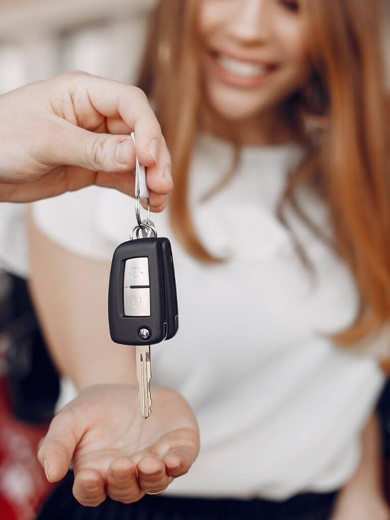 someone placing a car key in a woman's outstretched hand