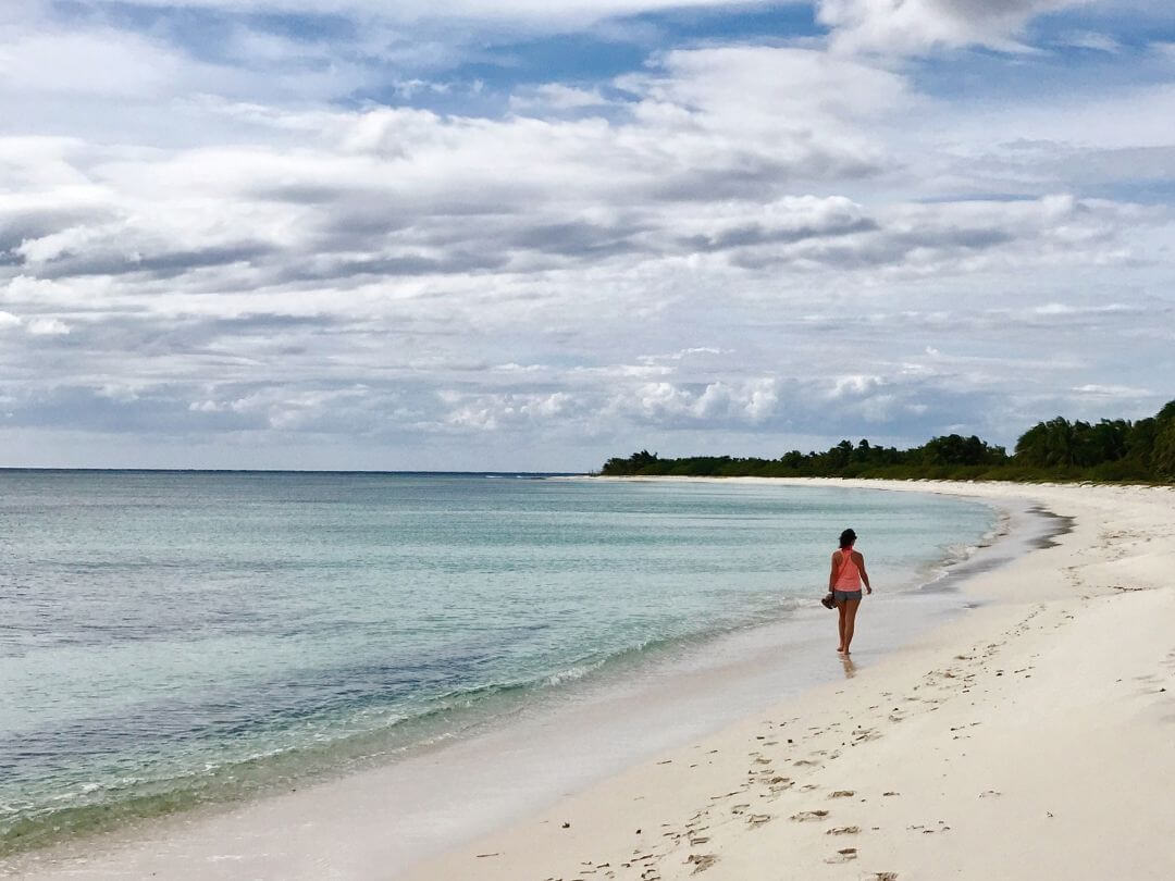 woman walks along the shore of El Cielo beach on Cozumel Island