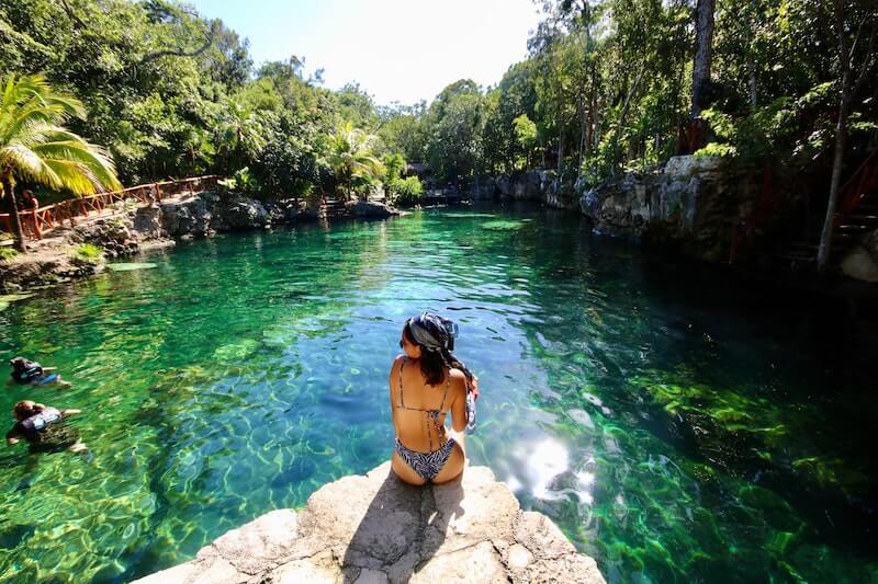 Solo female traveler sitting next to cenote in Riviera Maya, Mexico