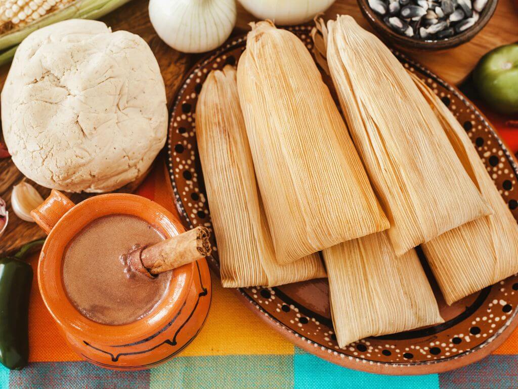 flat lay shot of tamales and hot chocolate on pottery dishes 