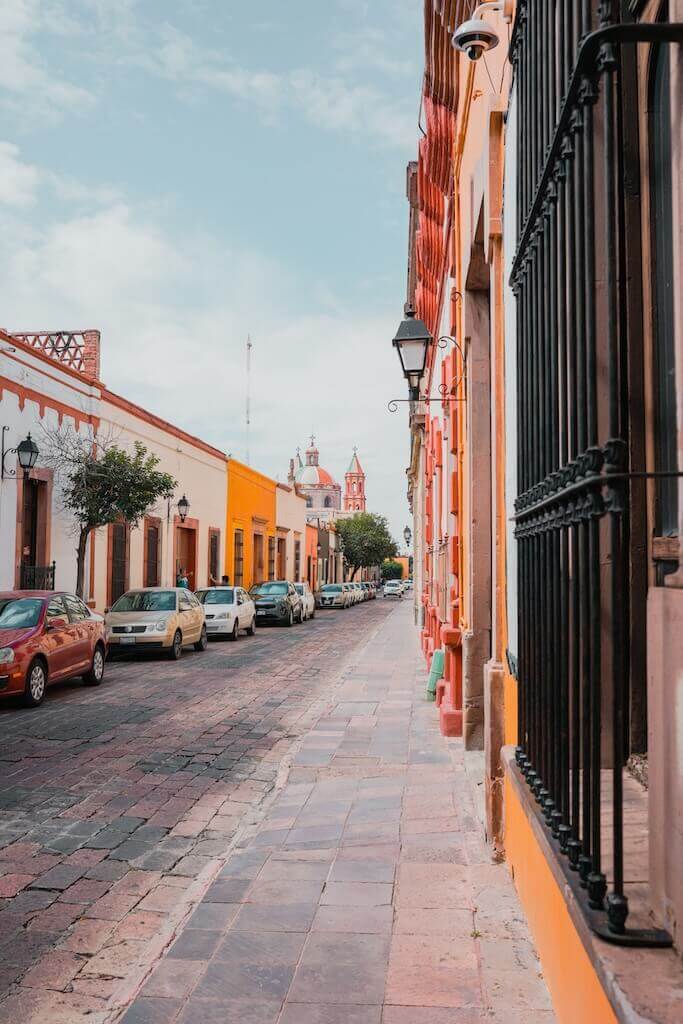 looking down the cobblestone street of Tequisquiapan, lined by colorful buildings