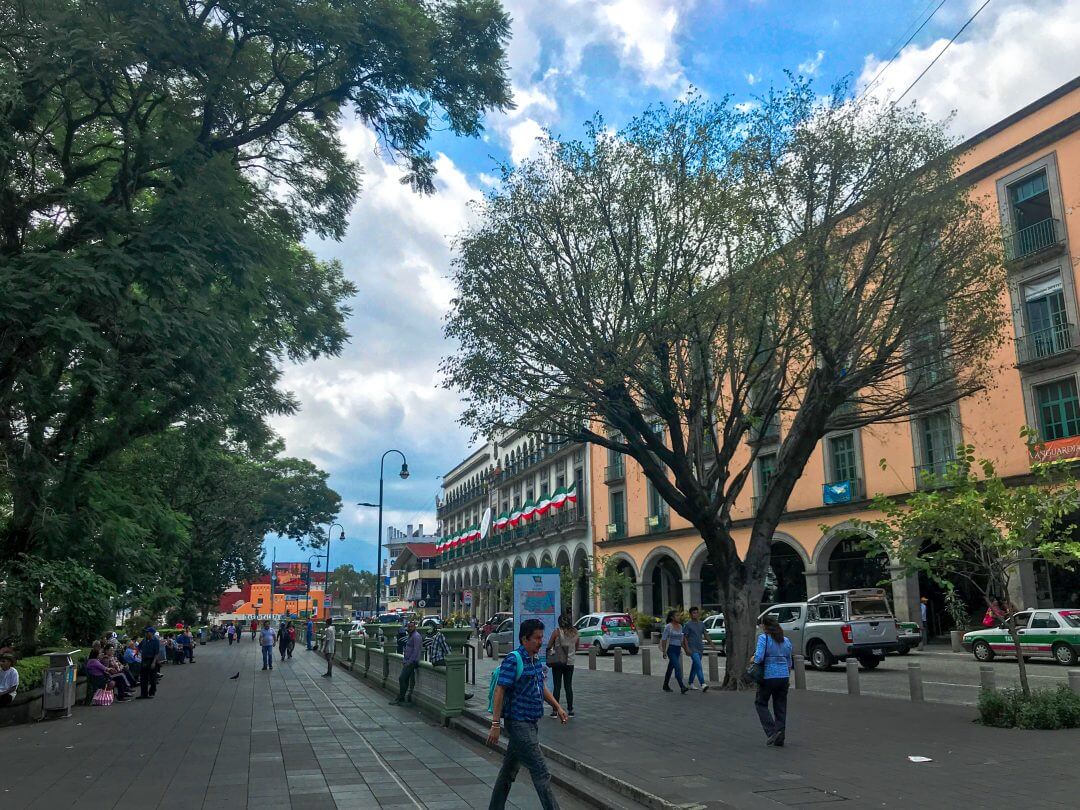 Looking down Xalapa's main street, calle Enriquez, with Parque Juarez on the left and the government palace to the right. Pedestrians cross the park in the distance