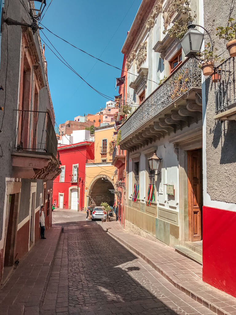 empty cobblestone street in Guanajuato, Mexico with colorful buildings on either side