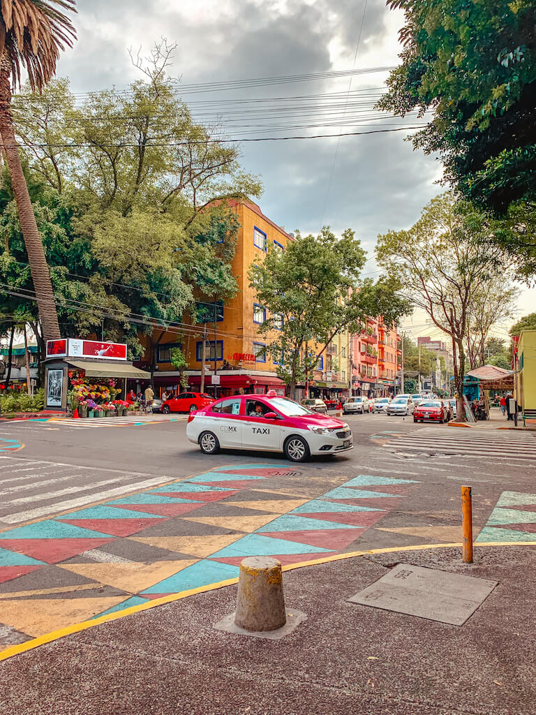 pink and white Mexico City taxi cab crosses an intersection in La Condesa, Mexico City