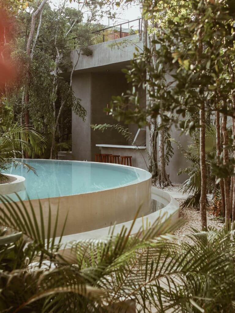 a lush jungle oasis surrounds a round concrete pool at a hotel in Tulum, Mexico