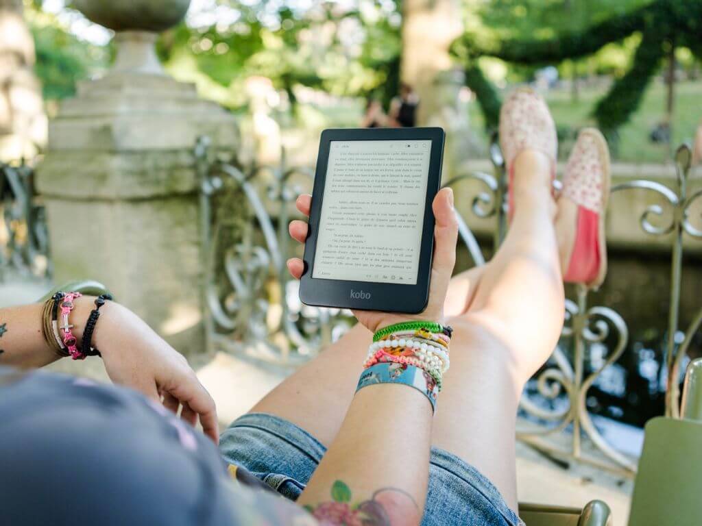 female traveler reading from an e-reader in a sunny destination