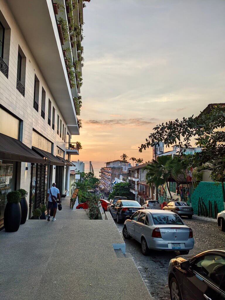 looking down a cobble stone street in Puerto Vallarta toward the sunset in front of the pier