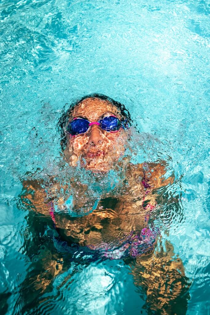 woman in swim goggles emerging from the pool 