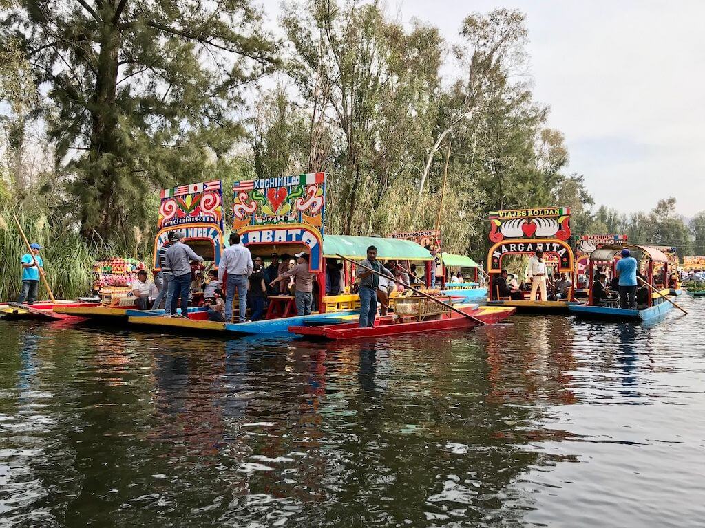 Trajinera boats paddle side by side in the Xochimilco canals of Mexico City